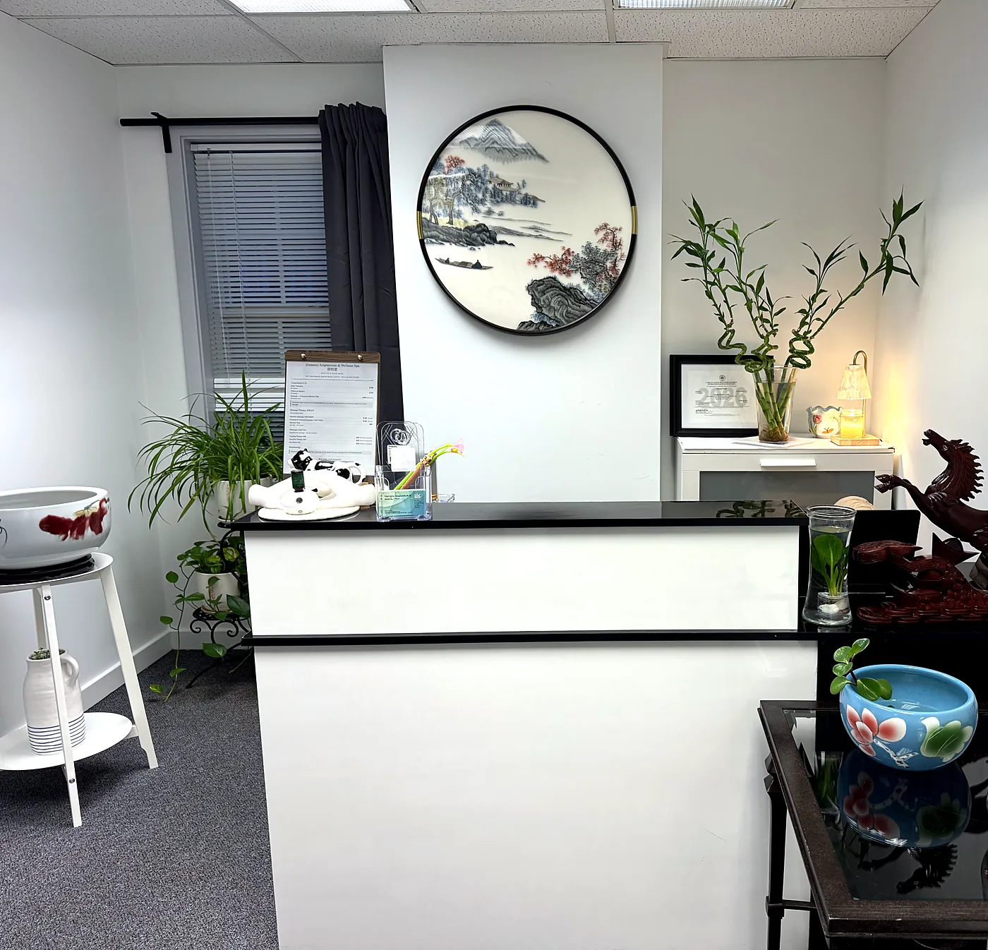 Reception desk with round Chinese embroidery art, lucky bamboo, and a framed license